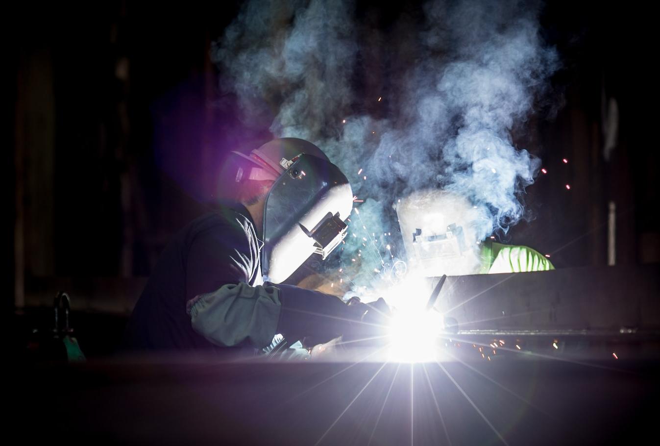 person welding metal using gray helmet